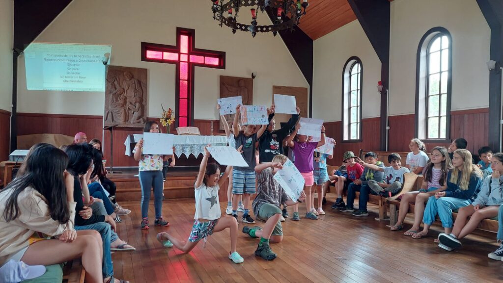 Campistas del campamento de niños muestran cartulinas al público de la iglesia de Puerto Fonck en el contexto de una dramatización
